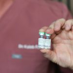 best-botox-kamloops-bc - Dr. Kaleb Falk Close-up of a Kamloops cosmetic injector holding two Dysport (botulinum toxin) vials, with a blurred clinical background.