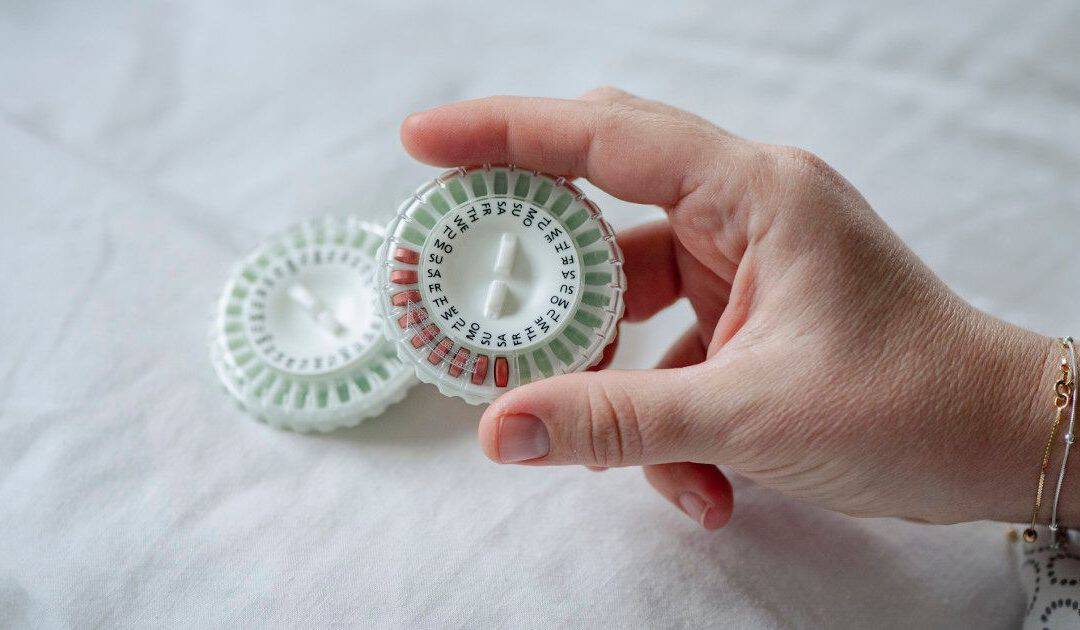 Hand holding weekly menopausal hormone therapy pills and vaginal estrogen inserts for menopause and perimenopause treatment in British Columbia.